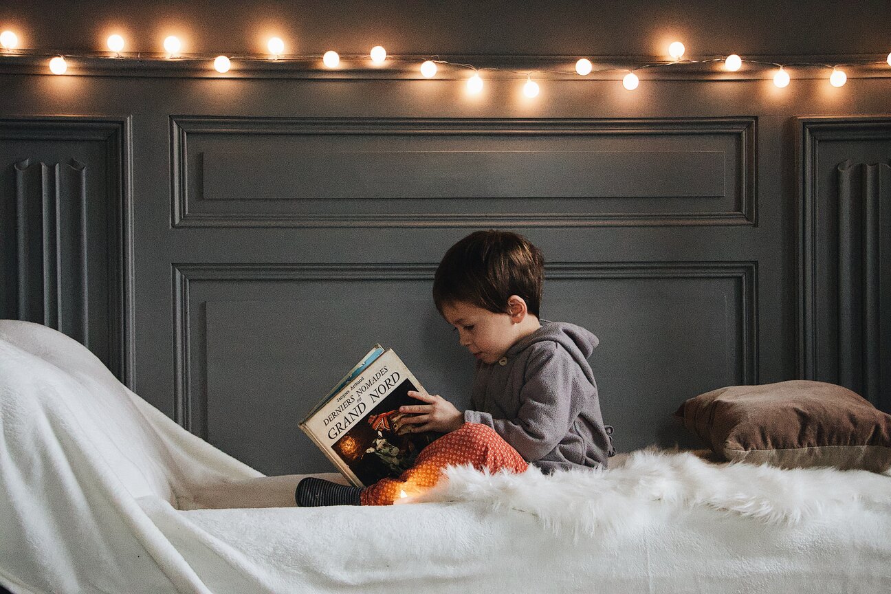 Boy on bed reading large hardback book