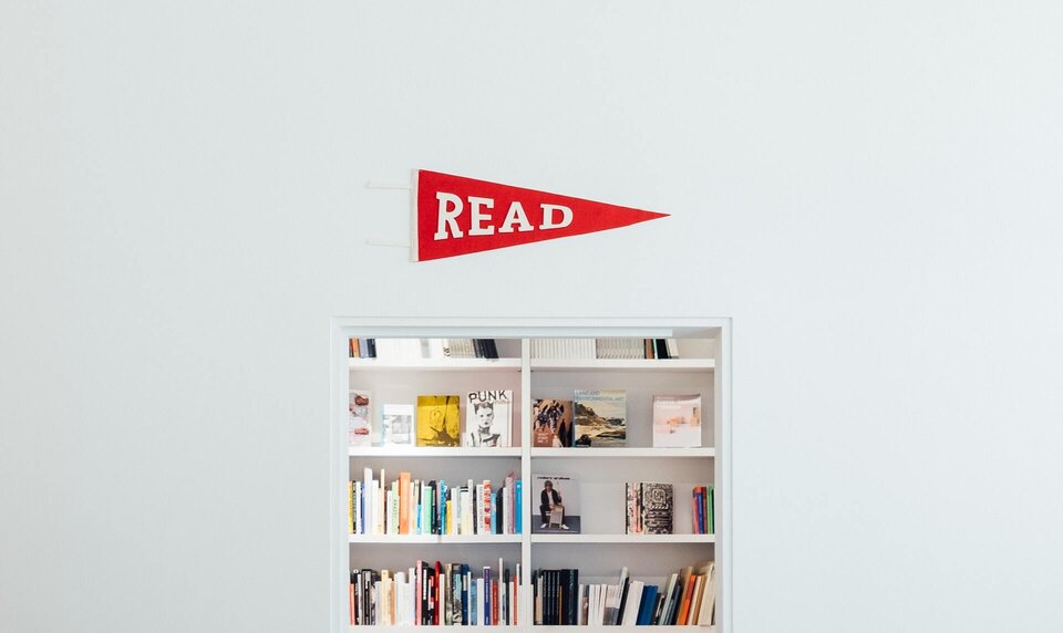 Photo of books on a shelf with a red sign about that says: Read